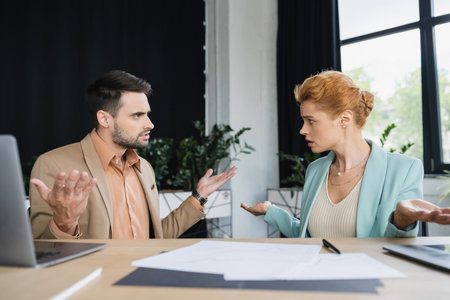 confused managers showing shrug gesture while talking near documents in office
