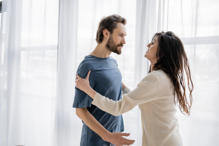 Aggressive man looking at frightened girlfriend during relationship crisis at home