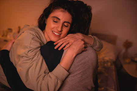 Carefree woman hugging boyfriend in bedroom in evening
