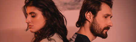 Sad couple with relationship difficulties sitting back to back at home in evening, bannerの写真素材
