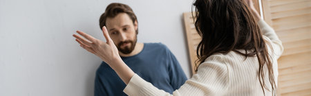 Brunette woman quarrelling with sad blurred boyfriend at home, bannerの写真素材