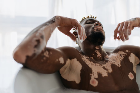 African american man with vitiligo taking bath at homeの写真素材