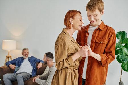happy mother with red hair holding hands with cheerful gay sonの写真素材