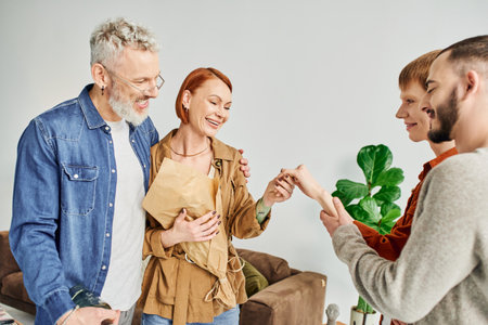 engaged gay man showing hand to happy parents near boyfriend at homeの写真素材