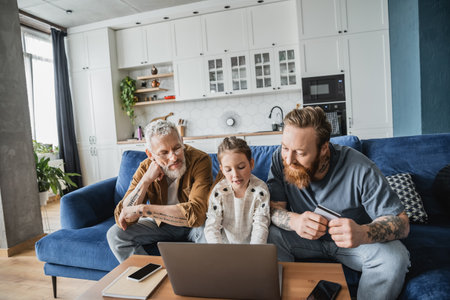 Gay parents with credit card looking at daughter using laptop at home