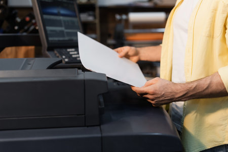 cropped view of publisher holding blank paper in print centerの写真素材
