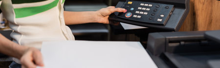 cropped view of publisher holding blank paper near printer in copy center, banner
