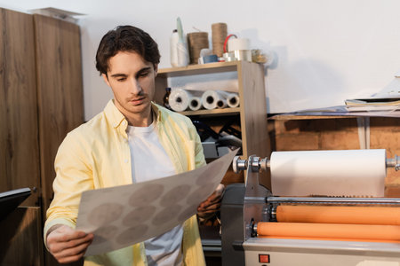 typographer looking at printed paper near professional print plotter