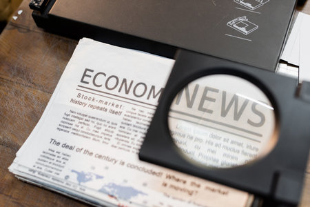 magnifying glass over newspapers with economic news in print centerの写真素材