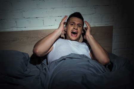 stressed man with panic attacks screaming while having nightmare at night