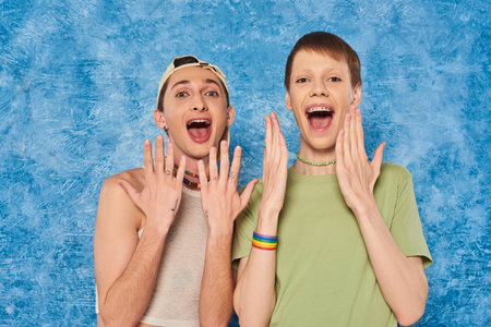 Shocked homosexual friends in casual clothes opening mouth and looking at camera during lgbt pride...