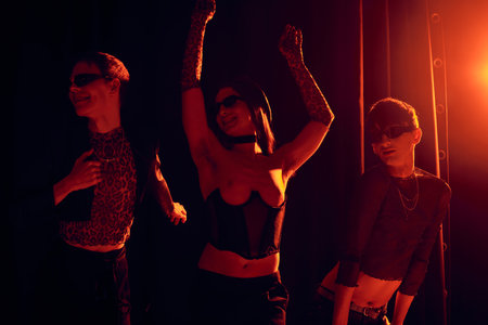 Excited group of gay friends in sunglasses and stylish clothes dancing during party and lgbt pride...