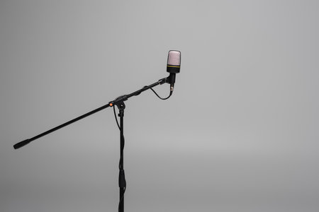 Black microphone with wire on metal stand isolated on grey with copy space, studio shotの写真素材