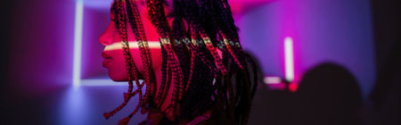 profile of young and captivating african american woman with dreadlocks posing on abstract purple background with radiant neon rays and lighting effects, bannerの写真素材