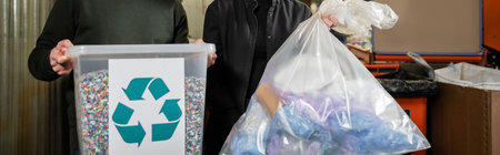Cropped view of volunteers holding trash bin with recycle sign and bag in blurred waste disposal...