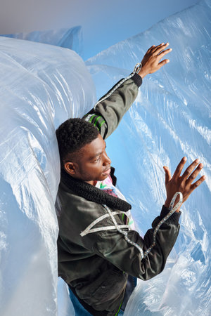 Young afroamerican man with trendy hairstyle wearing outwear jacket with led stripes touching glossy...