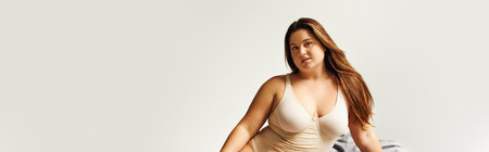 brunette plus size woman with natural makeup and long brunette hair wearing beige bodysuit and looking at camera, body positive, figure type, Caucasian, bannerの写真素材