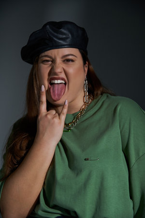 portrait of stylish plus size woman posing in leather beret and green t-shirt, looking at camera...