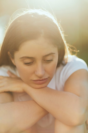 portrait of sad young woman with brunette long hair, in white polo shirt looking away, blurred...