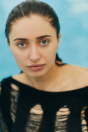 close up, natural beauty, no makeup look, sexy brunette woman in black knitted outfit posing inside of outdoor swimming pool during vacation in Miami, looking at camera, portraitの写真素材