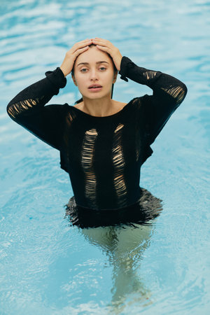 no makeup look, attractive and sexy brunette woman in black knitted outfit posing inside of outdoor...