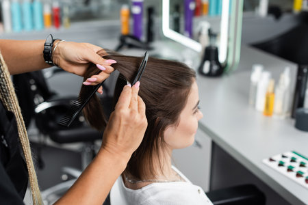 salon job, beauty worker brushing and clipping hair of woman, professional hair clip, comb, hairstyling, hair treatment, hairdo, extension, salon customer, beauty profession, high angle viewの写真素材