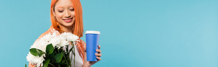 spring vibes, happy asian and young woman with red hair holding paper cup and bouquet of flowers on blue background, casual attire, generation z, coffee culture, coffee to go, bannerの写真素材