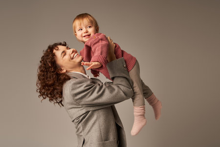 happy working mother, parenting and career, cheerful businesswoman lifting her toddler daughter on...