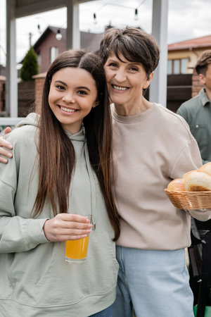 modern parenting, celebration of parents day, happy middle aged mother holding buns and hugging...