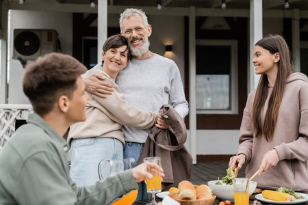happy marriage, celebrating parents day, cheerful middle aged couple hugging near joyful teenage...