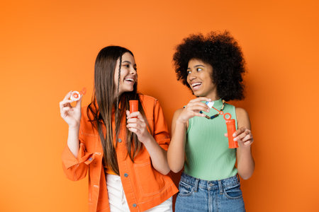 Positive and trendy multiethnic teenagers with bold makeup and casual outfits looking at each other...