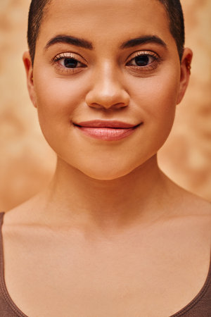 natural look, self-acceptance, young woman with short hair posing on mottled beige background, looking at camera, individuality, modern generation z, beauty and skincareの写真素材