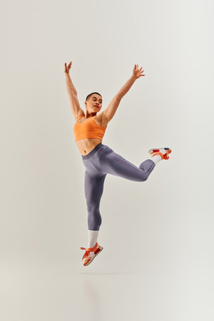 body positivity movement, young curvy and short haired woman jumping on grey background, female fitness, empowerment, motivation, working out, sportswear, strength and health, body imageの写真素材