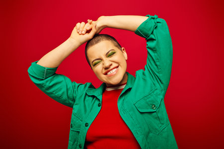 positive vibe, generation z, youth culture, young woman with short hair smiling with closed eyes on red background, fashion statement, youth culture, casual wear, vibrant backgroundの写真素材