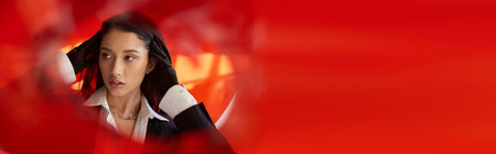 fashion forward, young asian model in white shirt and blazer posing in gloves behind red glass, personal style, youth trend, conceptual, touching neck and posing in studio, bannerの写真素材