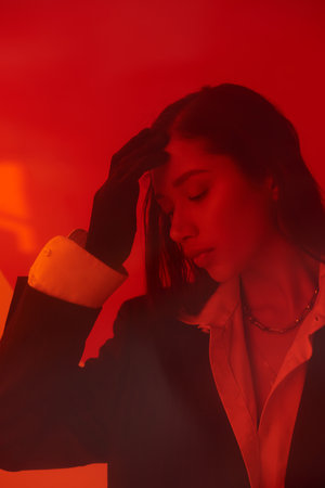 modern fashion, style and photography, young asian model in white shirt and blazer posing in gloves behind red glass, closed eyes, personal style, youth trend, conceptualの写真素材