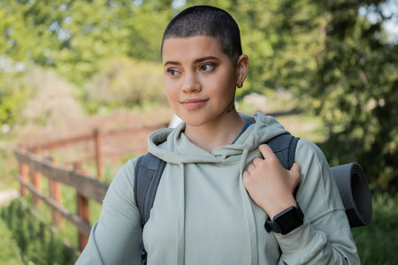 Portrait of young short haired and tattooed female traveler with fitness tracker and backpack...