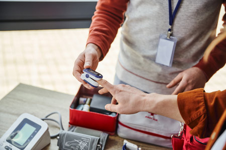 first aid training seminar, partial view of medical instructor with name tag measuring oxygen saturation of man with pulse oximeter, health care and emergency preparedness conceptの写真素材