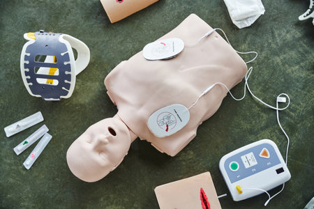 top view of CPR manikin near automated defibrillator, wound care simulators, neck brace and syringes...