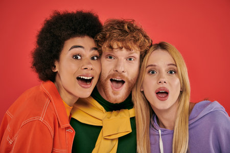 polyamorous concept, portrait of young man and multicultural women on coral background, studio shot, vibrant colors, love triangle, bonding and acceptance, excited polygamy loversの写真素材