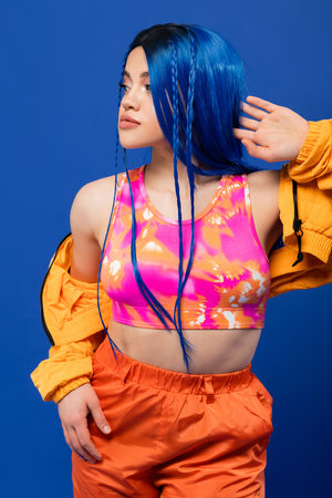 colorful clothes, dyed hair, female model with blue hair posing in puffer jacket on blue background, vibrant color, urban fashion, individualism, young woman with funky lookの写真素材