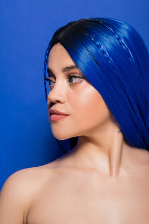 vibrant youth concept, tattooed young woman with dyed hair posing on blue background, hair color, individualism, female model with makeup and trendy hairstyle, vibrant youthの写真素材