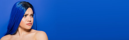 portrait of dissatisfied woman with dyed hair looking away on blue background, hair color, individualism, female model with makeup and trendy hairstyle, vibrant youth, emotional, bannerの写真素材