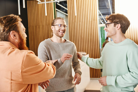 cheerful entrepreneurs in eyeglasses and stylish casual clothes discussing startup project near...