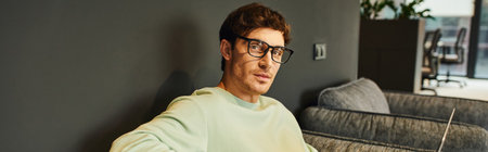 portrait of stylish businessman in casual clothes and eyeglasses looking at camera in contemporary office environment, professional headshot, confidence and success concept, bannerの写真素材