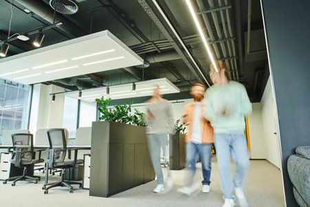 team of energetic entrepreneurs walking along contemporary coworking space with high tech interior, office furniture and green natural plants, movement, long exposure, dynamic businessの写真素材