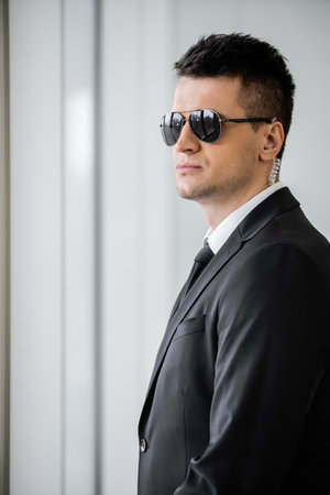 professional headshots, bodyguard with earpiece, good looking man in sunglasses and black suit with...