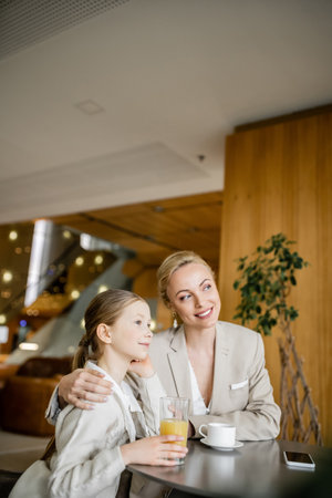 happy mother and daughter spending quality time, blonde woman hugging preteen girl and looking away...