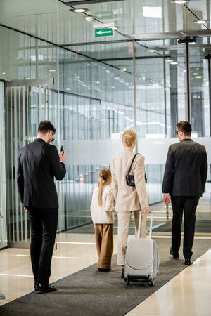 personal protection, bodyguards in formal wear and sunglasses escorting blonde woman and her daughter, leaving hotel, private safety, rich lifestyle, security serviceの写真素材