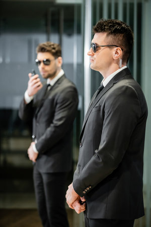 bodyguard service, private security, professionals in suit and sunglasses standing in hotel lobby, handsome man with earpiece, communication, luxury hotel, vigilance, protection and workの写真素材